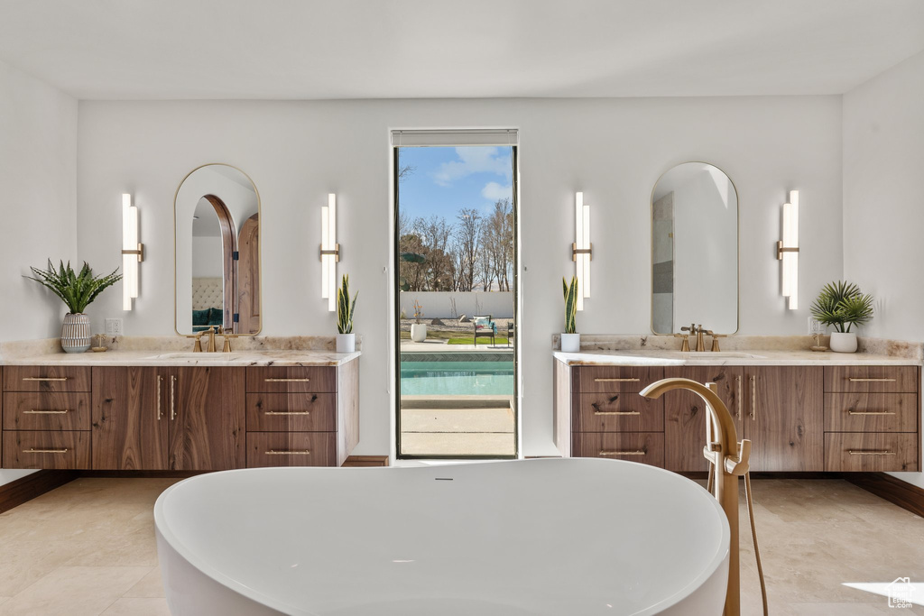 Full bathroom featuring a freestanding tub, two vanities, and a sink
