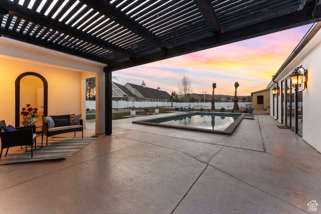 Pool at dusk featuring a patio area, a fenced in pool, fence, and a pergola