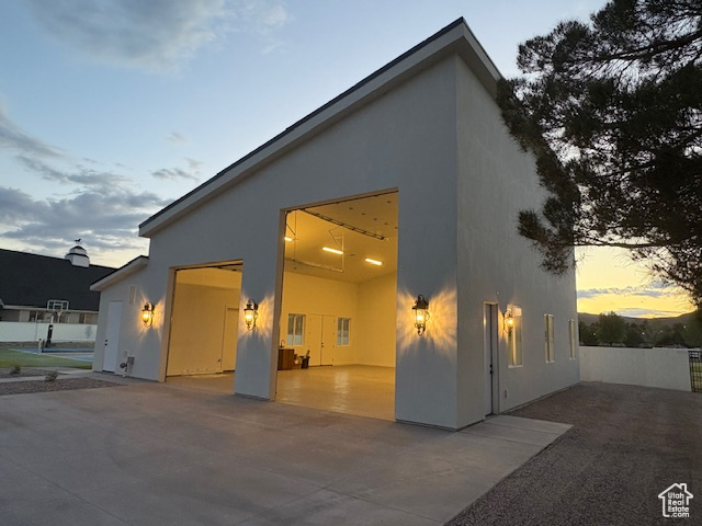 View of front of property with stucco siding, a garage, and a patio area