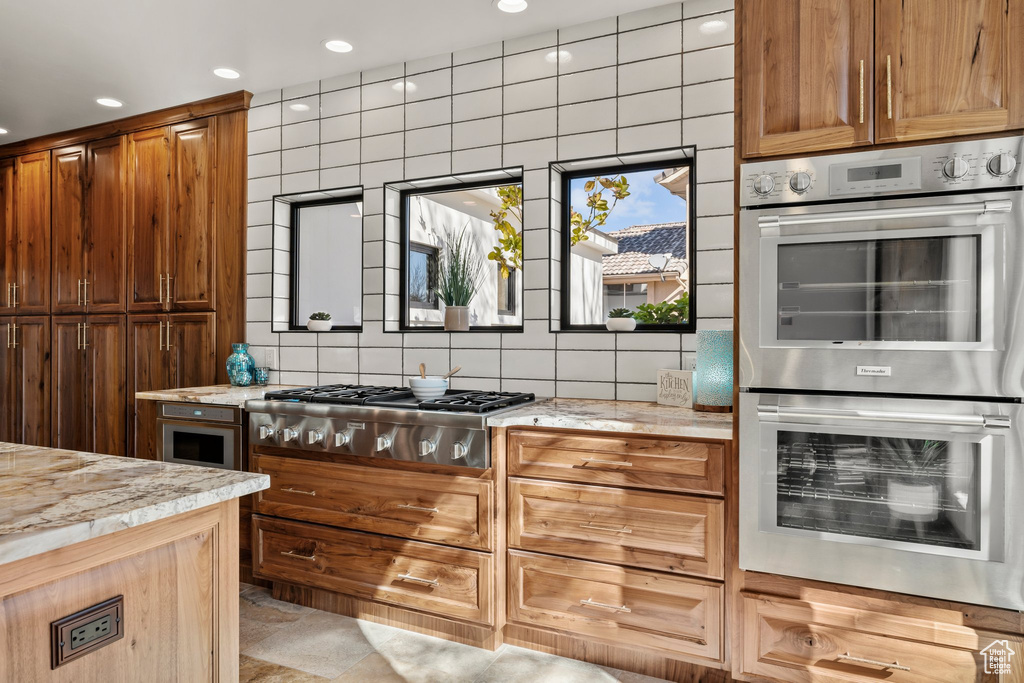 Kitchen featuring stainless steel appliances, recessed lighting, light stone counters, and tasteful backsplash