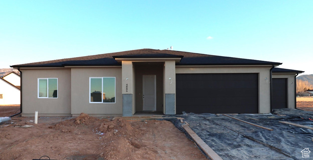 Prairie-style home with stucco siding, a garage, and aphalt driveway