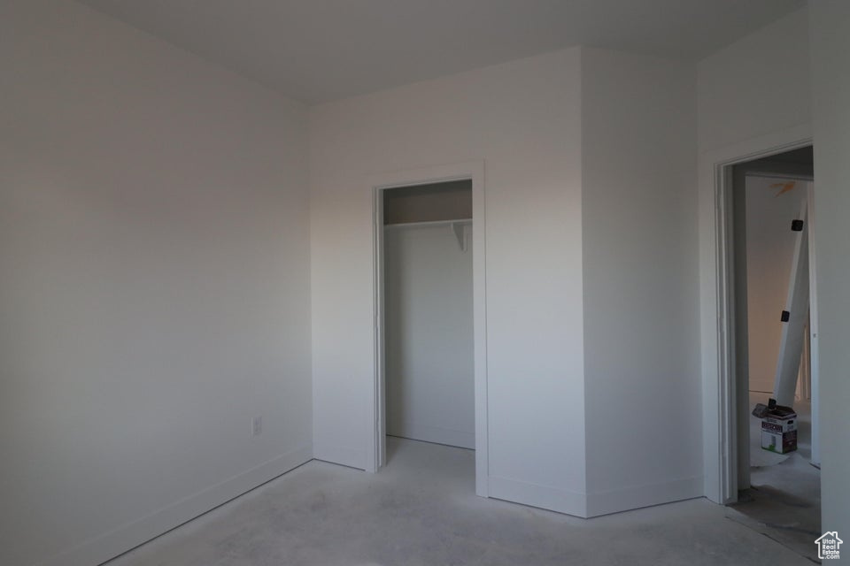 Unfurnished bedroom with concrete flooring, baseboards, and a closet