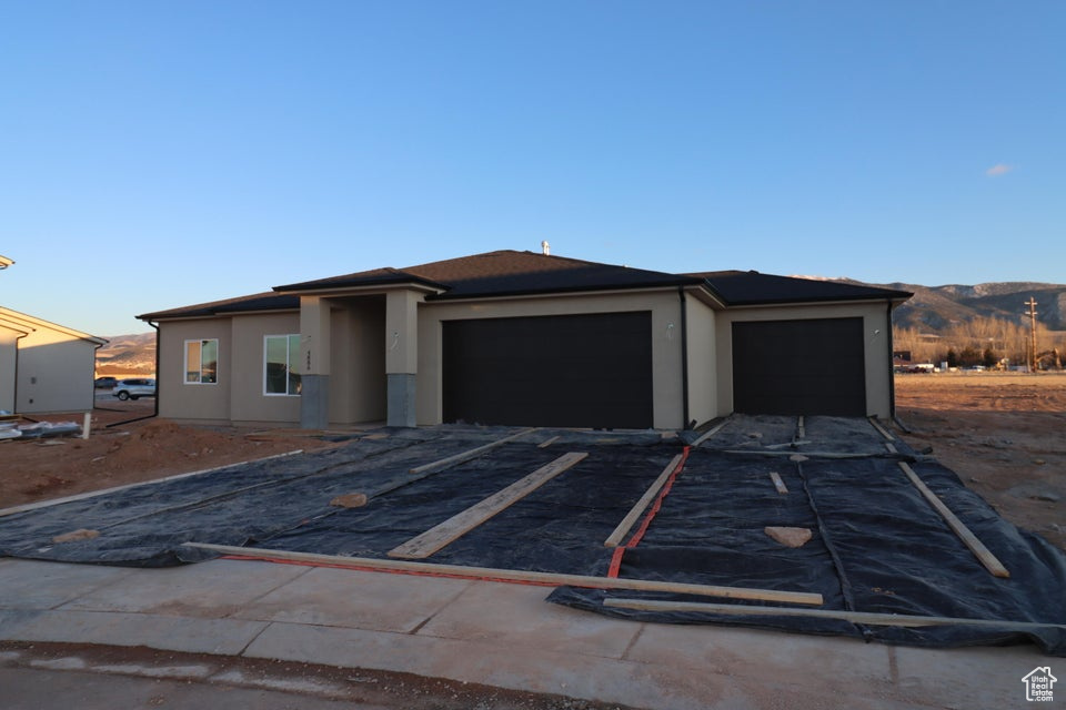 View of front of home with a mountain view, stucco siding, a garage, and aphalt driveway