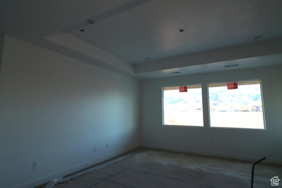 Spare room with a tray ceiling, baseboards, and visible vents