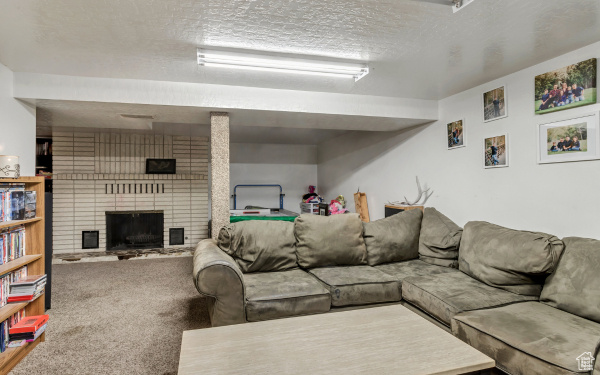 Carpeted living room featuring a textured ceiling and a brick fireplace