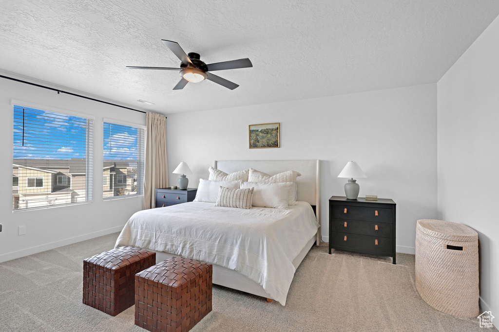 Bedroom with a textured ceiling, baseboards, a ceiling fan, and carpet