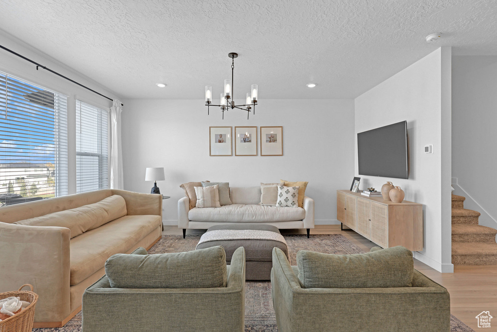 Living area featuring recessed lighting, an inviting chandelier, light wood-type flooring, and a textured ceiling