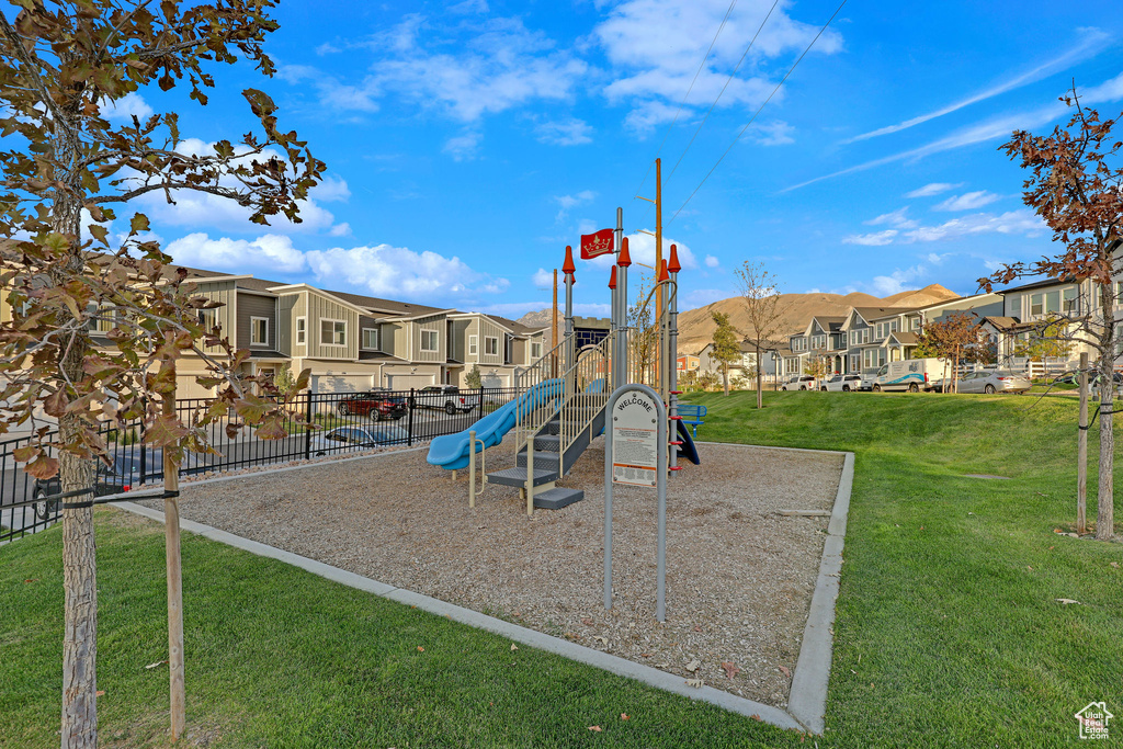 Community playground with a lawn, a residential view, and fence