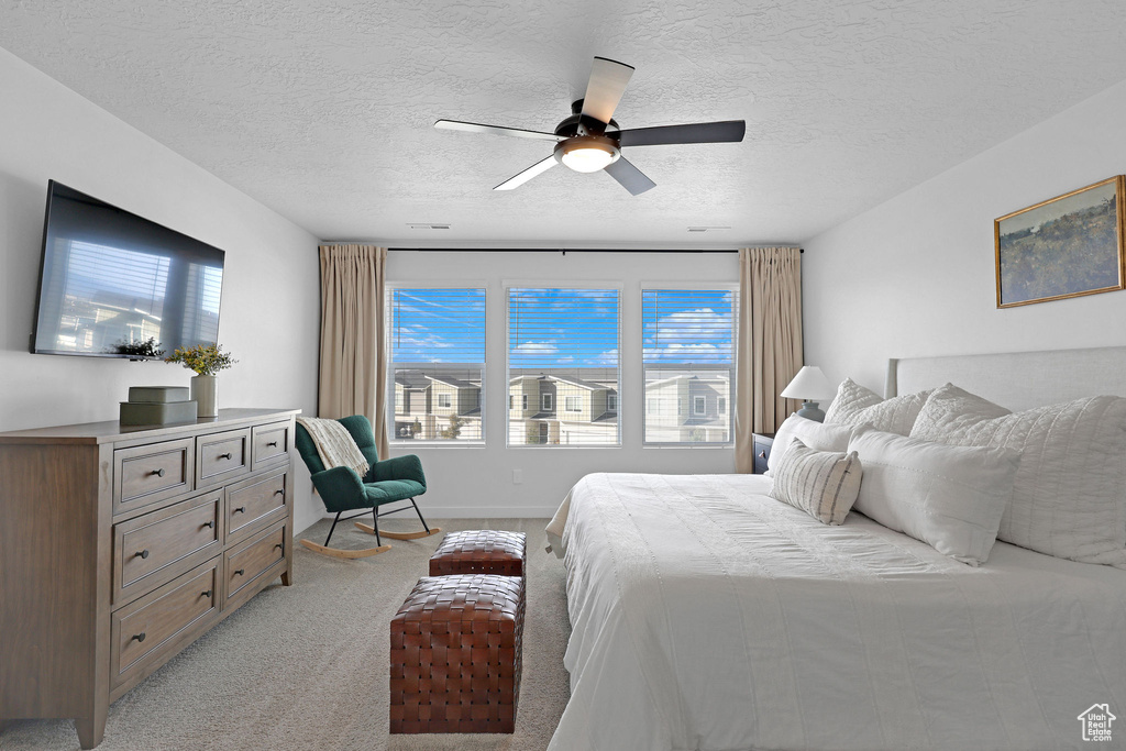 Bedroom featuring light colored carpet, a textured ceiling, and ceiling fan