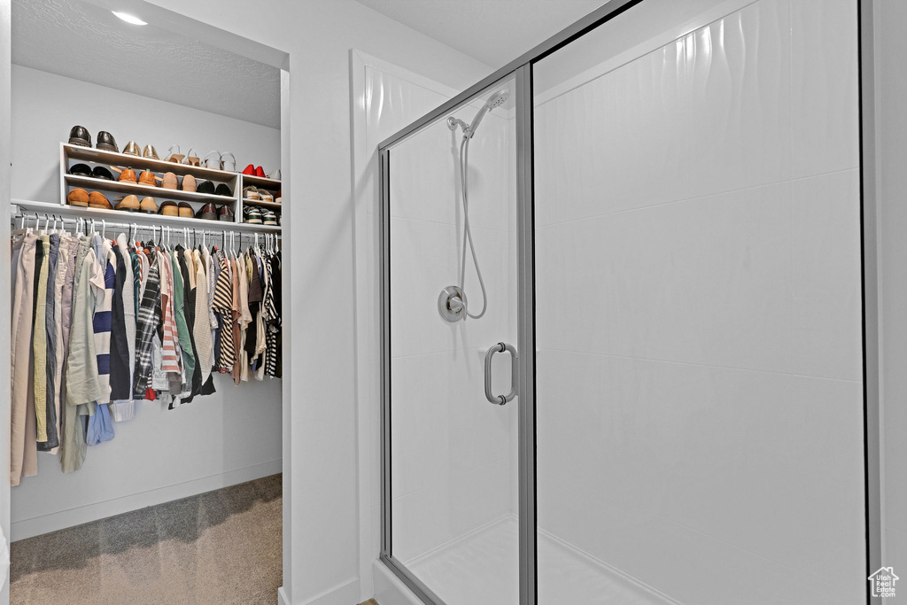 Full bathroom with a shower stall, baseboards, and a walk in closet