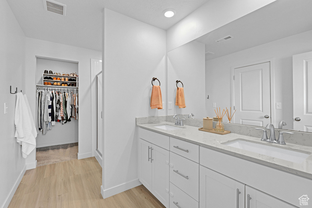 Full bathroom featuring visible vents, wood finished floors, baseboards, and a sink