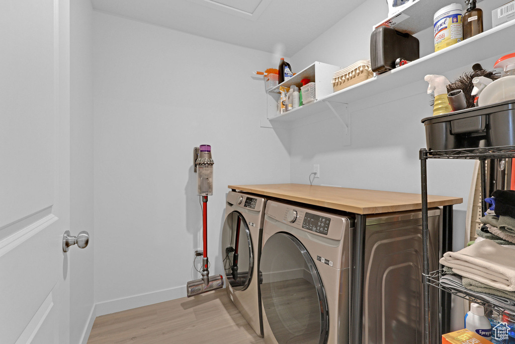 Washroom with laundry area, washer and clothes dryer, baseboards, and light wood-type flooring