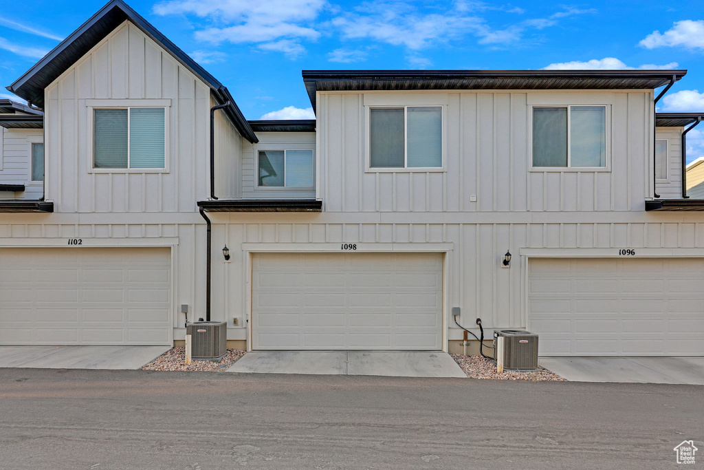 View of property featuring a garage, cooling unit, and board and batten siding