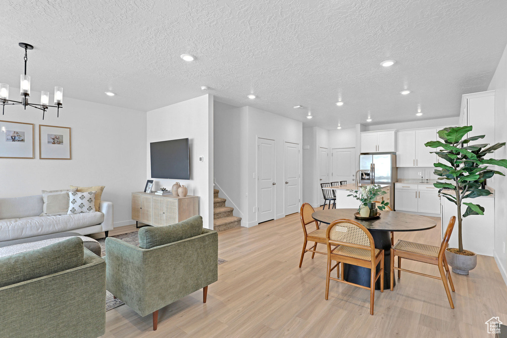 Dining room featuring recessed lighting, light wood-style flooring, a chandelier, and a textured ceiling