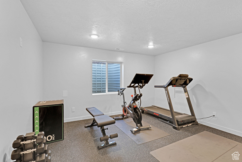 Exercise room with a textured ceiling and baseboards