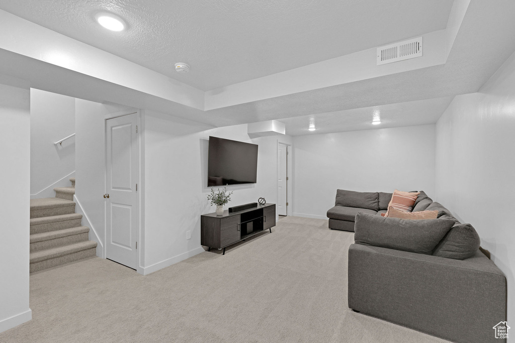 Living area featuring stairway, light colored carpet, baseboards, and visible vents