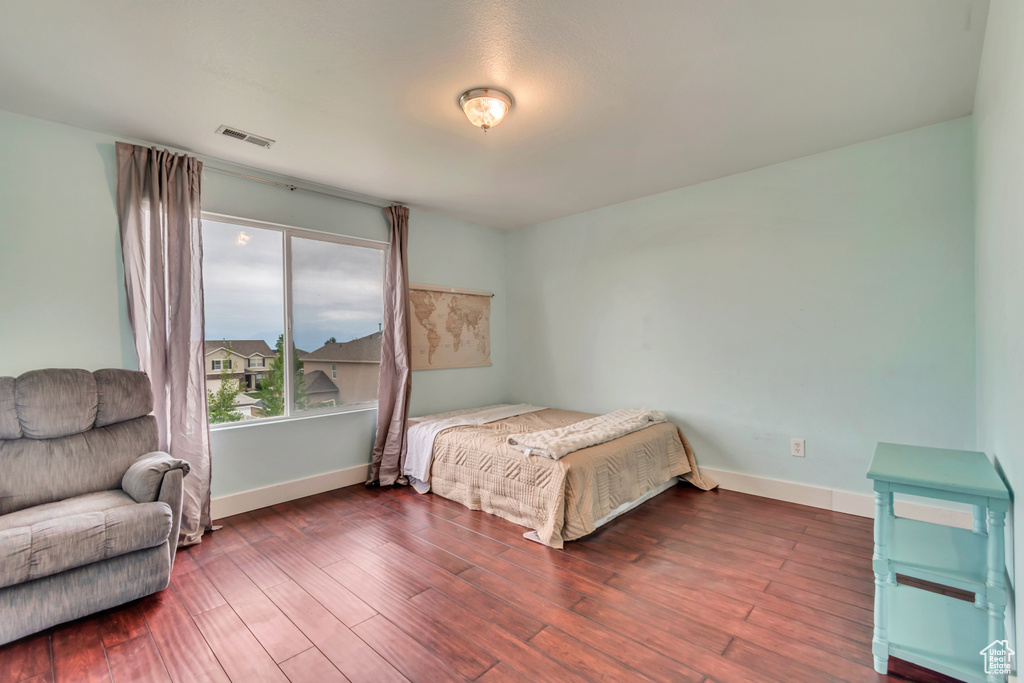 Bedroom with wood finished floors, visible vents, and baseboards