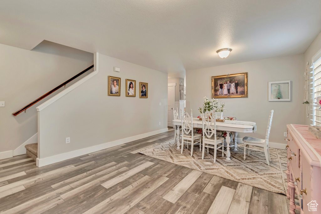 Dining space with stairs, baseboards, and wood finished floors