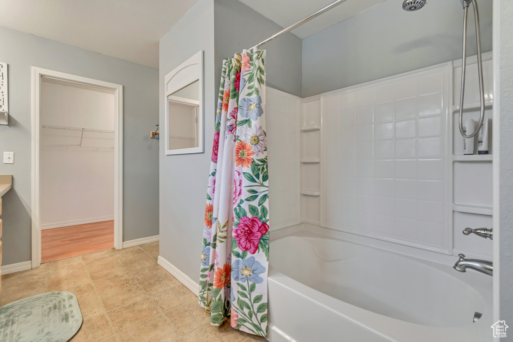 Bathroom featuring shower / bath combination with curtain, tile patterned flooring, and baseboards