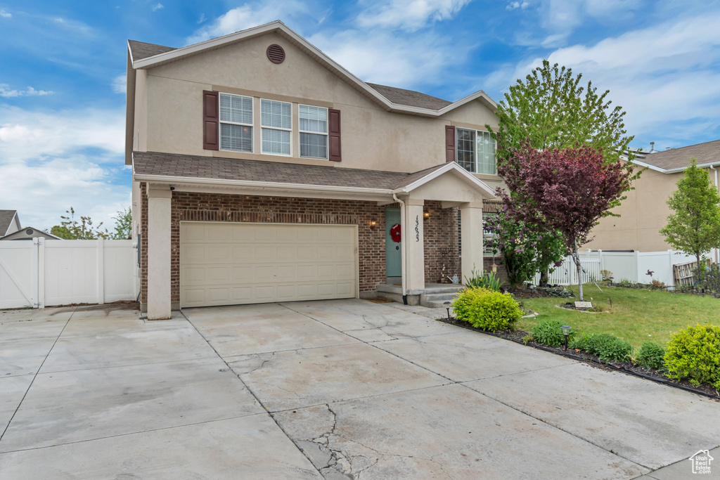 Traditional-style home with a front yard, driveway, fence, and a garage