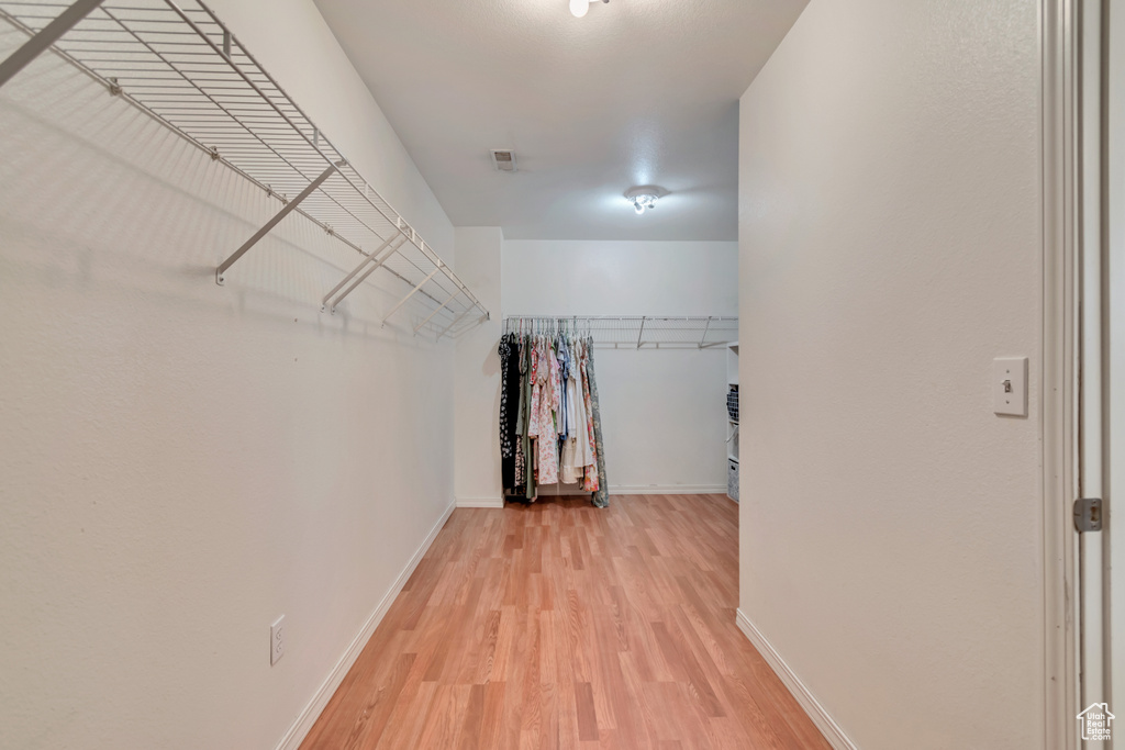 Walk in closet with light wood-style floors