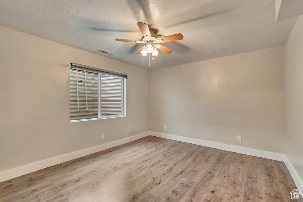 Unfurnished room featuring a textured ceiling, baseboards, ceiling fan, visible vents, and wood finished floors