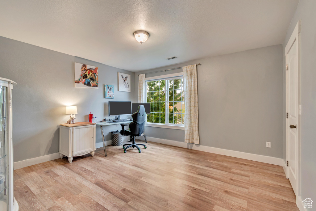 Office with light wood-type flooring, baseboards, and visible vents