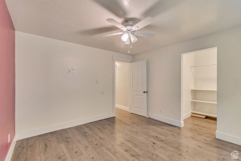 Unfurnished bedroom with baseboards, light wood-style floors, and a walk in closet