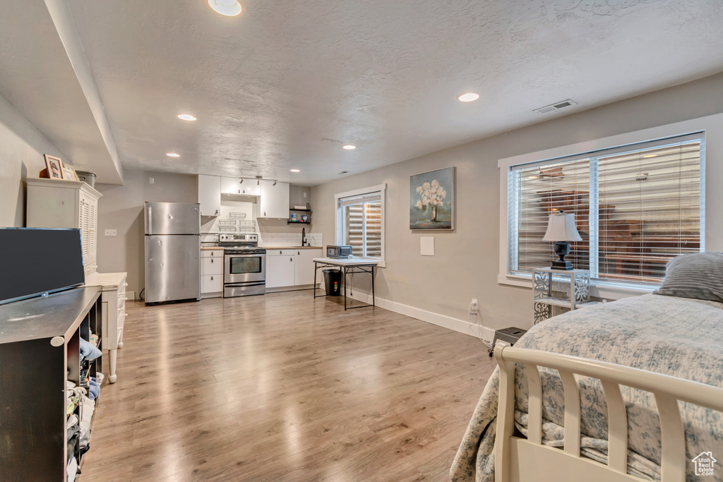 Bedroom featuring light wood-style flooring, freestanding refrigerator, visible vents, baseboards, and recessed lighting