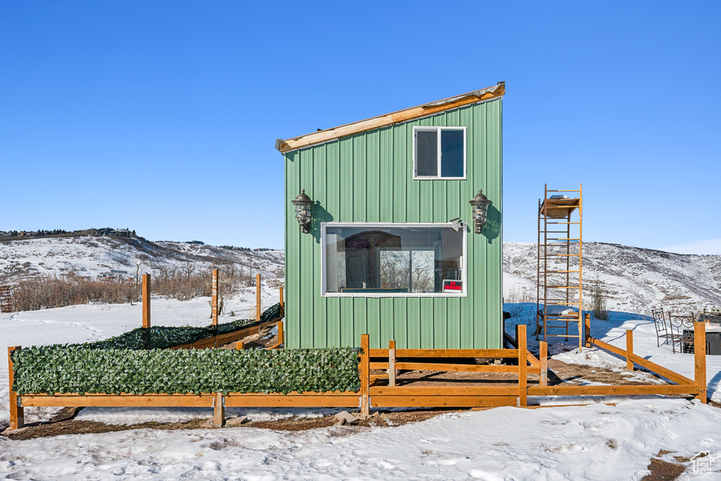 Snow covered structure featuring a mountain view and fence private yard