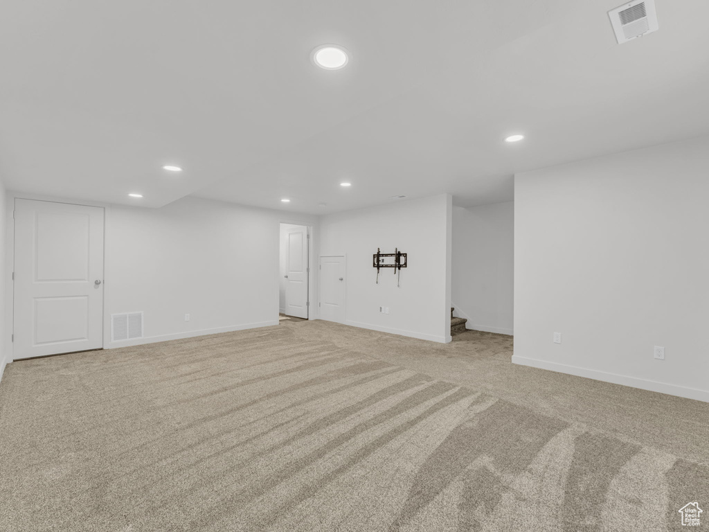 Finished basement with light carpet, baseboards, visible vents, and recessed lighting