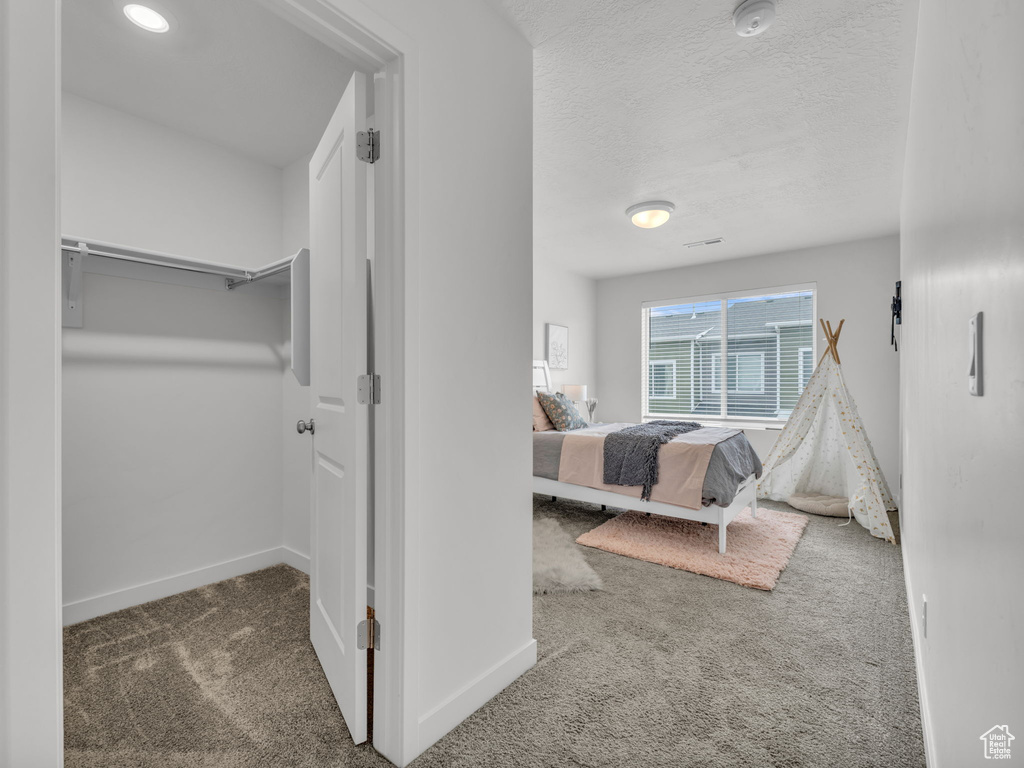 Bedroom with a textured ceiling, carpet, and baseboards