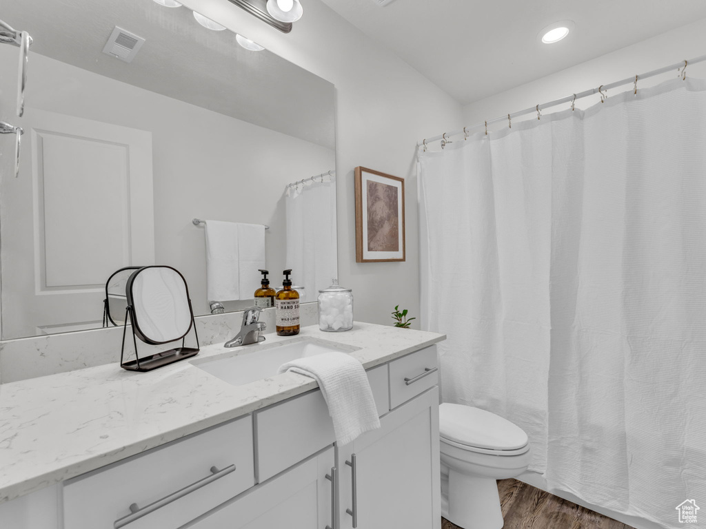 Bathroom featuring toilet, wood finished floors, vanity, visible vents, and recessed lighting