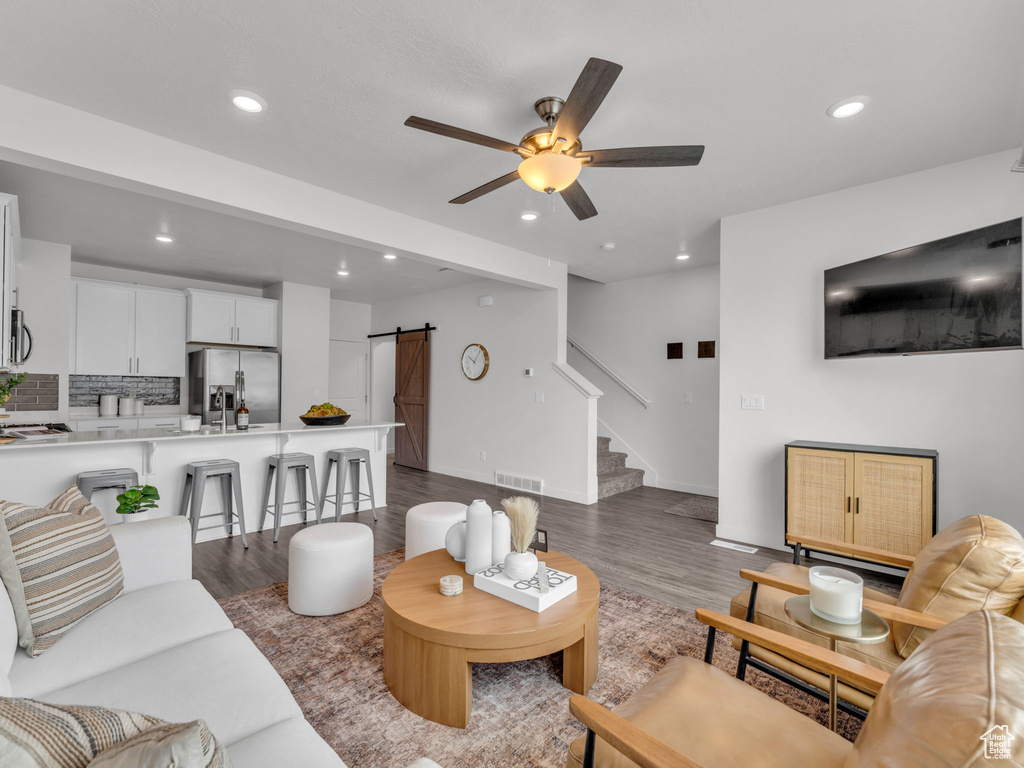 Living room with dark wood-style flooring, visible vents, a barn door, and recessed lighting