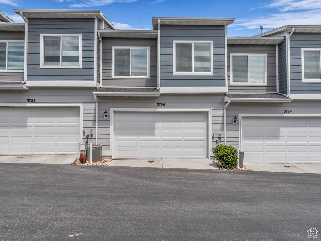 Townhome / multi-family property with cooling unit and a garage