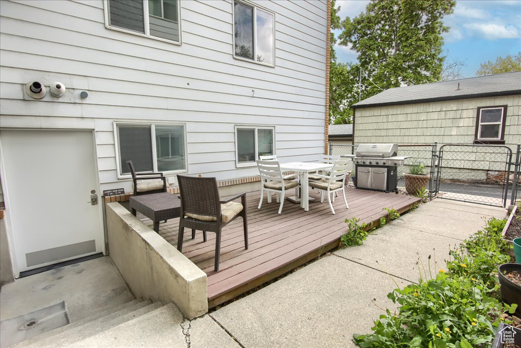 Wooden deck with a gate, fence, outdoor dining space, and grilling area