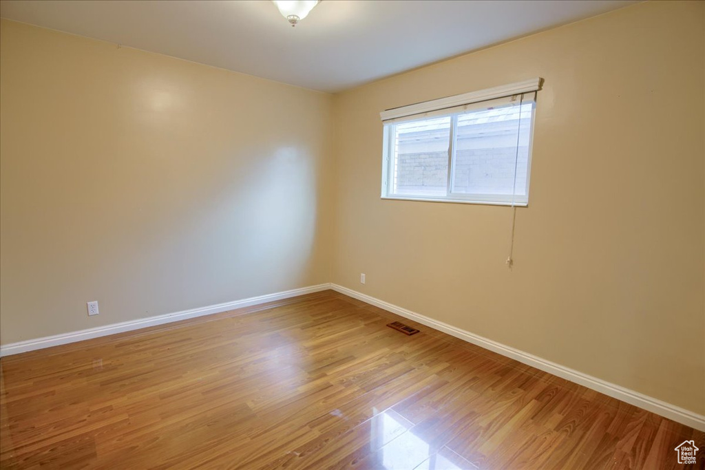 Unfurnished room with visible vents, light wood-style flooring, and baseboards