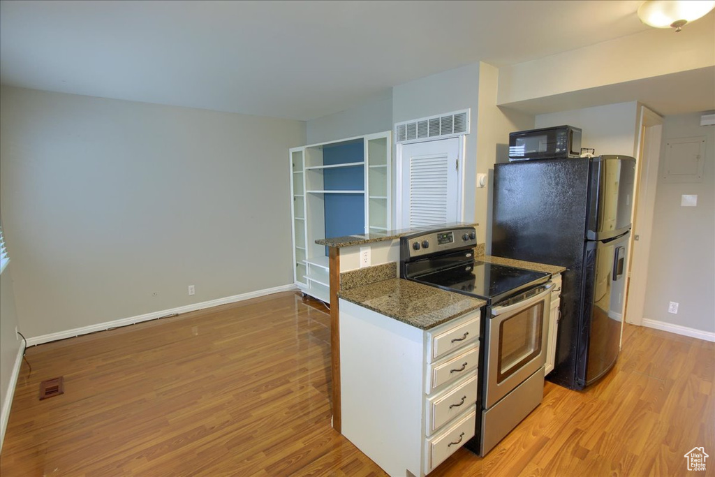 Kitchen with light wood-style floors, visible vents, baseboards, and black appliances