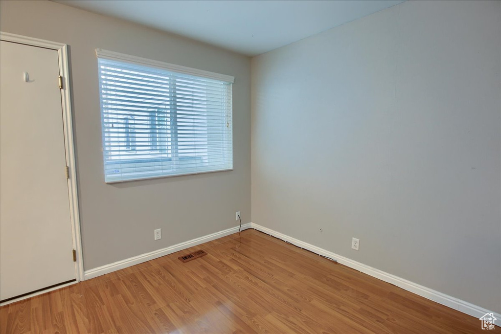 Empty room featuring baseboards, visible vents, and wood finished floors