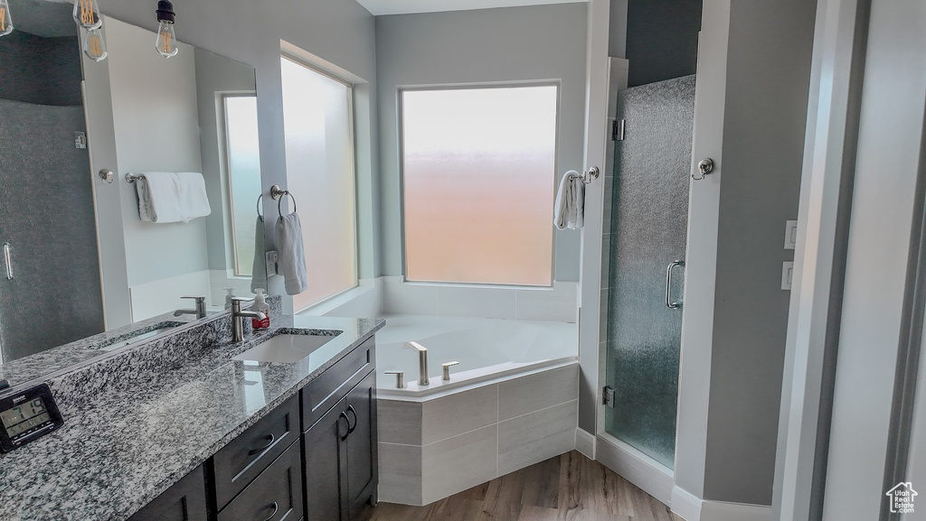 Full bath featuring a garden tub, a shower stall, a healthy amount of sunlight, and wood finished floors