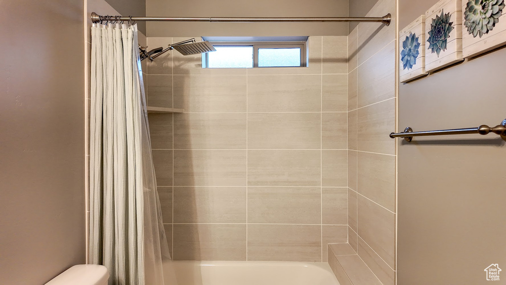 Bathroom featuring toilet and shower / tub combo with curtain