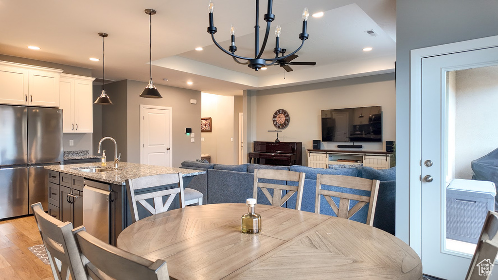 Dining room featuring light wood-type flooring, visible vents, recessed lighting, a chandelier, and a raised ceiling