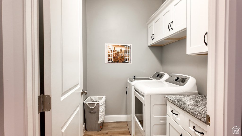 Laundry room with cabinet space, washing machine and clothes dryer, light wood finished floors, and baseboards