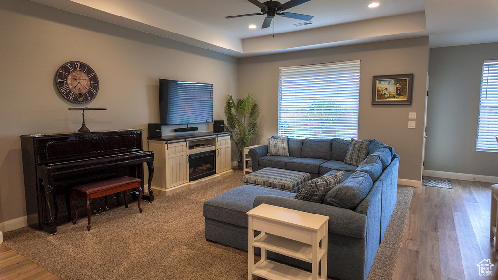 Living room with visible vents, recessed lighting, a ceiling fan, a raised ceiling, and baseboards