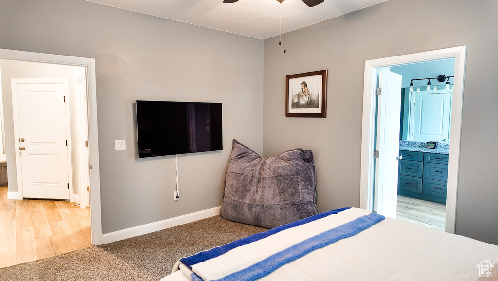 Bedroom featuring light carpet, ensuite bathroom, baseboards, and light wood-style floors