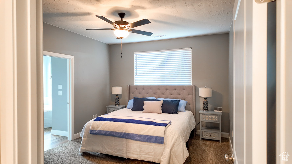 Carpeted bedroom with visible vents, baseboards, and a ceiling fan