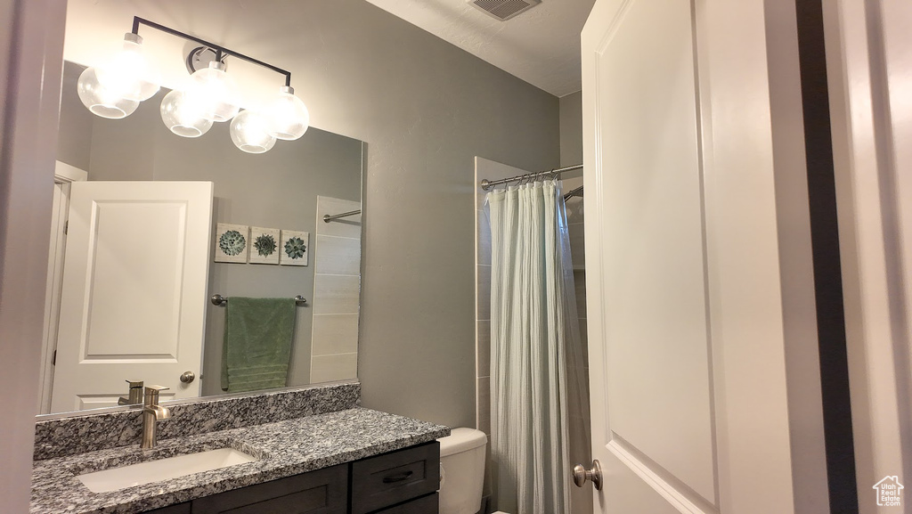 Full bathroom featuring toilet, vanity, visible vents, and curtained shower