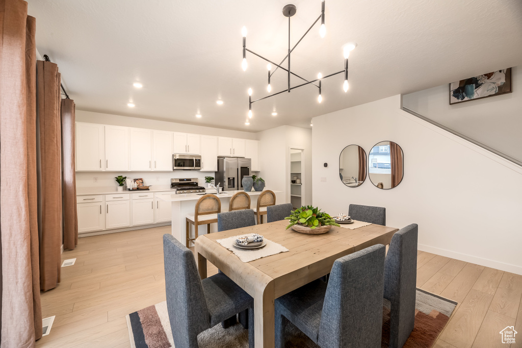 Dining space with baseboards, a notable chandelier, light wood-style floors, and recessed lighting