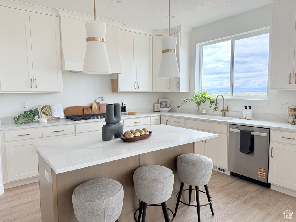 Kitchen featuring stainless steel appliances, a sink, a kitchen breakfast bar, light wood-style flooring, and a kitchen island