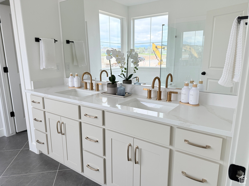 Bathroom with a shower stall, tile patterned floors, and double vanity
